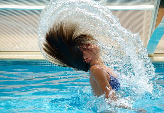 a woman is playing her hair in the swimming pool